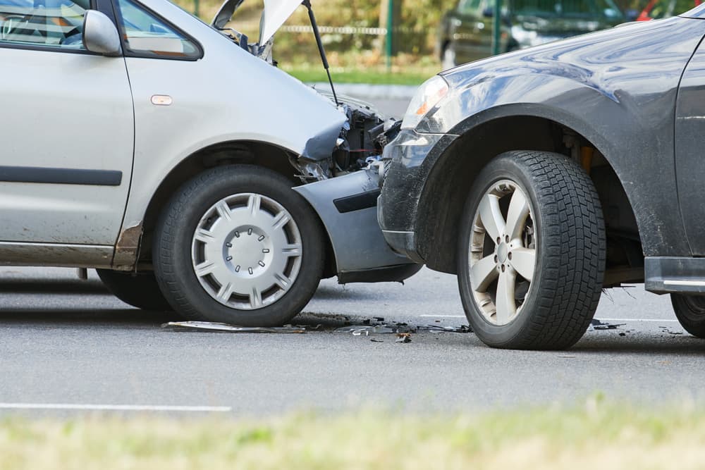 Insurance officer takes notes while agent inspects black car post-accident.