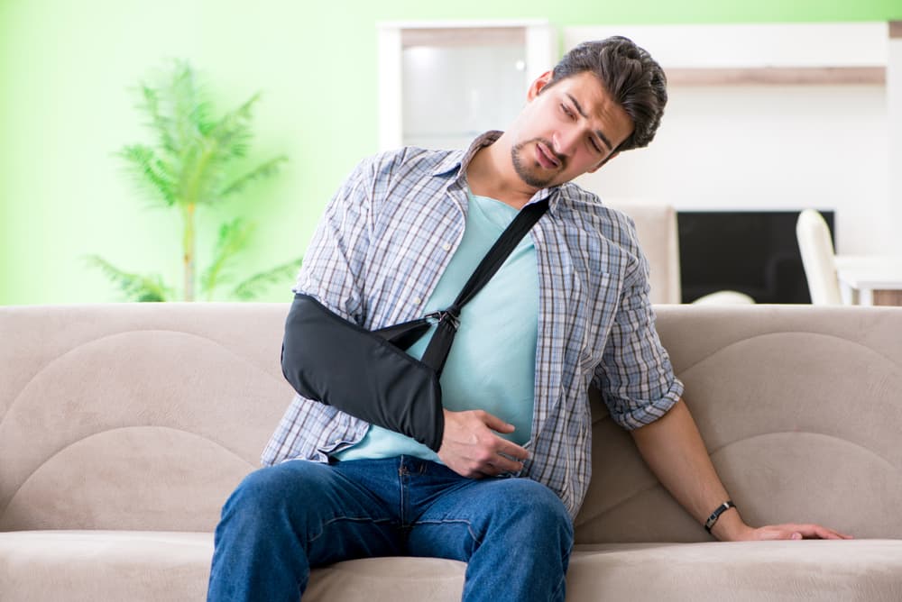 Young man with hand injury seated on sofa following motorcycle accident.