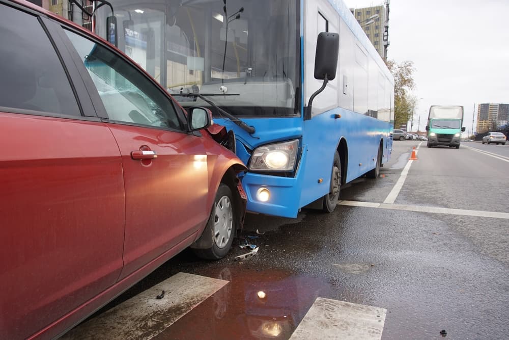 Car and bus collide head-on at pedestrian crossing. Traffic accident scene.