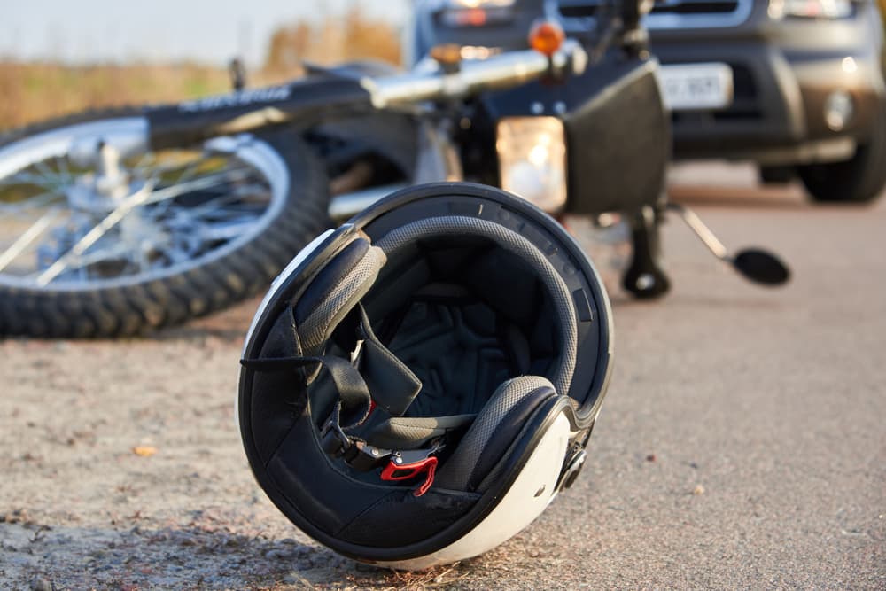 Image depicting a car, helmet, and motorcycle on the road, illustrating the concept of road accidents in Calgary.