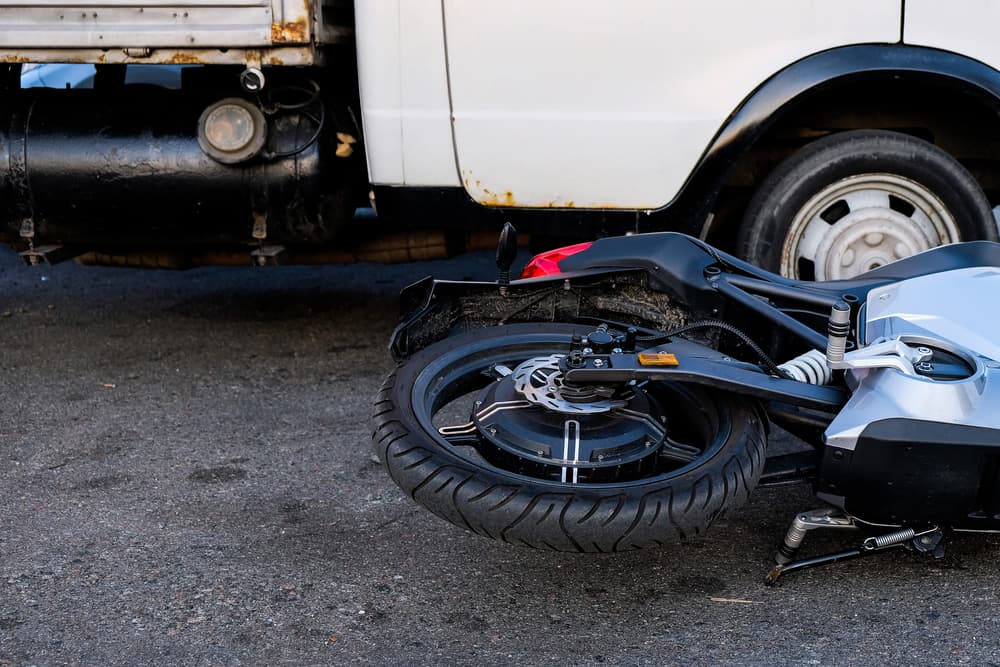 Electric motorcycle and cargo vehicles after a road accident. Concept of riding safety in city traffic.
